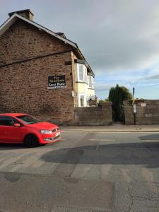 a red car parked in front of a brick building at Station Guesthouse - Self entry via keypad inc parking in Lancaster
