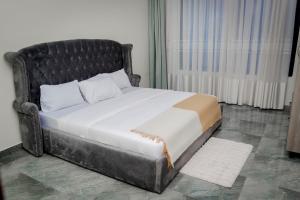 Un dormitorio con una cama grande con cabecero negro. en La Petite Résidence, en Kigali