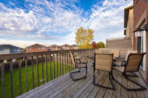 a deck with two chairs and a table on it at Stylish and Cozy 4 bedroom House in Barrie
