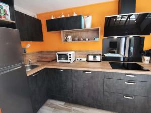 a kitchen with black cabinets and an orange wall at Résidence Oucanes - Superbe T3 avec accès direct aux pistes de Réallon OUC7 MAE-8401 in Réallon