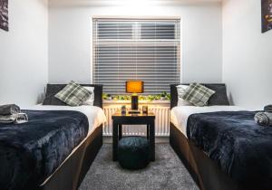 a bedroom with two beds and a table with a lamp at The Cave in Coventry
