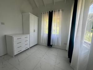 una camera da letto bianca con cassettiera e finestre di Seaview Oasis a Castries