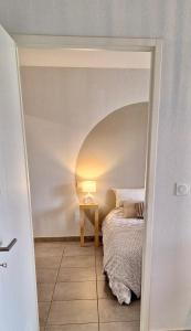 a bedroom with a bed and a table with a lamp at L'échiquier de Béziers - T2 déco soigné - Belle terrasse -Parking - Wifi in Béziers