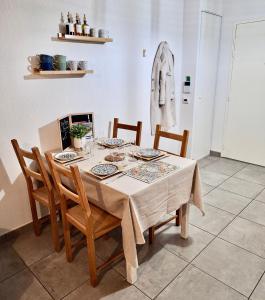 a dining room with a table with chairs and a coat on the wall at L'échiquier de Béziers - T2 déco soigné - Belle terrasse -Parking - Wifi in Béziers