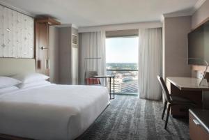 a hotel room with a white bed and a desk and a window at Norfolk Waterside Marriott in Norfolk