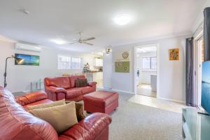 a living room with red leather furniture and a kitchen at Lorikeet Retreat 2 Pet Friendly Air Conditioned Holiday House in Shoal Bay