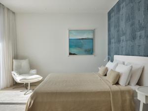a bedroom with a large bed and a chair at H2O Art Beach Villa Crete in Agios Nikolaos +59 photos