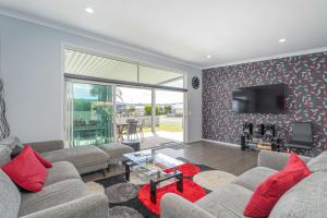 a living room with two couches and a tv at Hosts on the Coast Belair Bach in Whitianga