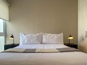 a bedroom with a white bed with two lamps at Duplex with Balcony in Barranco in Lima