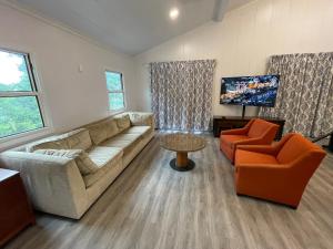 a living room with a couch and two chairs and a television at Great Cistern Beach Village in Marsh Harbour