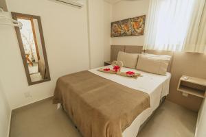 a bedroom with a bed with flowers and a mirror at Apê aconchegante a 50m do mar - Maracaípe in Porto De Galinhas