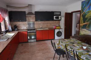 a kitchen with red cabinets and a table with a table cloth at Aeropuerto Ezeiza Nuevo Descanso in Monte Grande