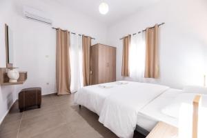 a white bedroom with a white bed and a window at Etheria Apartment in Artemida