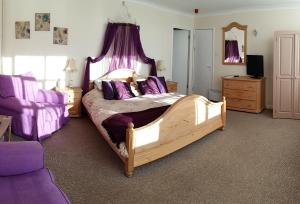 a bedroom with a large wooden bed with purple pillows at Staden Grange in Buxton