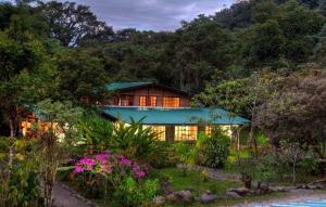 ein Haus mit grünem Dach im Wald in der Unterkunft Rio Quijos EcoLodge in El Chaco