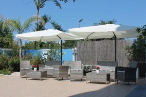 朱利亞諾瓦的住宿－藍色海洋公寓式酒店，庭院里摆放着一组椅子和遮阳伞