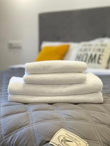 four white towels stacked on top of a bed at Oberig Royal Apartments НОВОБУДОВА, найкращий район, дуже ЧИСТО in Chernivtsi