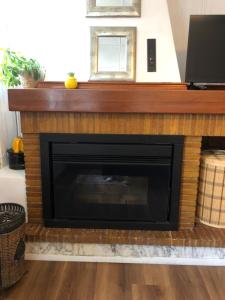 a brick fireplace with a wooden mantle above it at O lar da praia in Corcubión