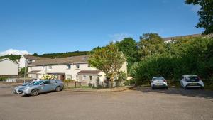 two cars parked in a parking lot in front of a house at Charming 2BD House - Parking & Garden in Oban in Oban