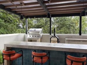 an outdoor kitchen with a grill and stools at Luxury apartment 10 min to Airport Be Cariari Condo #402 in La Asunción