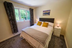 a bedroom with a bed with yellow pillows and a window at Charming 2BD House - Parking & Garden in Oban in Oban