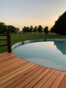 a swimming pool on a wooden deck with a field at El Hornero in San Andrés de Giles