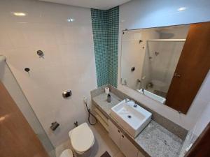 a bathroom with a sink and a toilet and a mirror at Lindo Apt Beira Mar Guarapari in Guarapari +16 photos