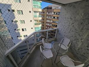 a balcony with chairs and a table and a building at Lindo Apt Beira Mar Guarapari in Guarapari