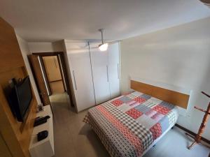 a bedroom with a bed and a tv in it at Lindo Apt Beira Mar Guarapari in Guarapari