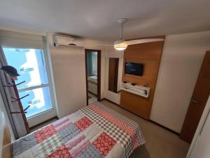 a small bedroom with a bed and a television at Lindo Apt Beira Mar Guarapari in Guarapari
