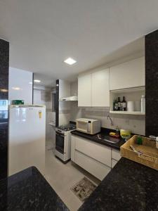 a kitchen with white cabinets and a white refrigerator at Lindo Apt Beira Mar Guarapari in Guarapari