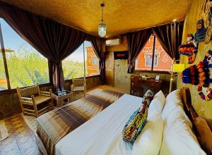 a bedroom with a large bed in a room with windows at Riad Chay & Boutique in Ouarzazate