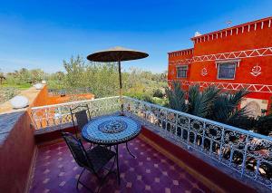 a balcony with a table and chairs and an umbrella at Riad Chay & Boutique in Ouarzazate