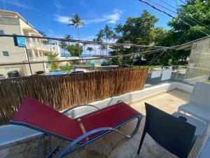 una silla roja y una silla en el balcón en Big Blue Apartments, en Cabarete