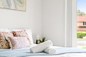 a white bedroom with a bed with pillows and a window at Cozy Double Room in Panania - Close to Stations & Stores - Shared Bathroom in Panania