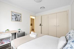 a white bedroom with a bed and a desk at Cozy Double Room in Panania - Close to Stations & Stores - Shared Bathroom in Panania
