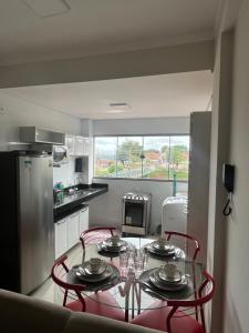 a kitchen with a table with red chairs and a kitchen with a refrigerator at Apartamento no Centro in Paracatu