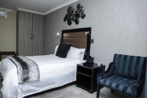 a hotel room with a bed and a chair at Q's Boutique Stay in Standerton +36 photos