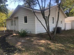 a white house with a tree in front of it at Walnut River's Edge Guesthouse in El Dorado