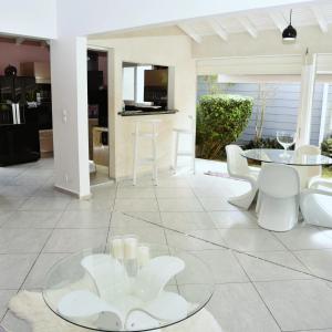 a living room with a glass table and white chairs at Villa confortable à Sainte-Anne avec piscine privée in Sainte-Anne