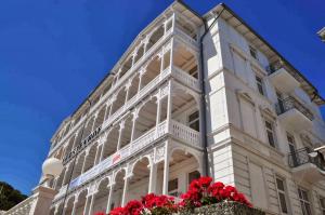 un edificio blanco con flores rojas delante de él en Fürstenhof - Ferienwohnung 202, en Sassnitz