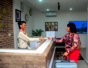 two women are shaking hands at a cash register at Five Clover Monastery Road in Lagos