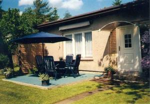 a patio with a table and chairs under an umbrella at Ferienhaus Mattke in Sassnitz