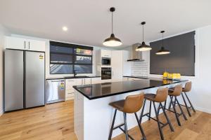Una cocina con gabinetes blancos y una encimera con taburetes. en Tairanga View, en Queenstown