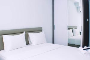 a bedroom with two white pillows and a mirror at Simply and Well Design Studio Room at Patraland Urbano Apartment By Travelio in Bekasi +15 photos