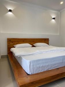 a wooden bed with white sheets and two pillows at B2 Hotel Savannakhet in Savannakhet