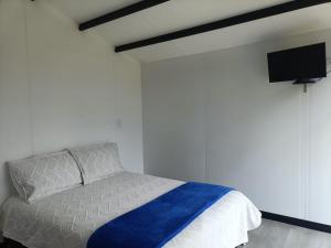 a bedroom with a bed and a flat screen tv at LA ESTANCIA DE FRANCIA Paipa in La Bolsa