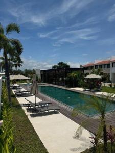 a swimming pool with chairs and umbrellas next to a building at Comfort at Club De Golf el Tigre in Nuevo Vallarta 