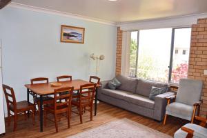 a living room with a table and a couch at Traveller's Palms no 8 - Bring your own linen. in South West Rocks +2 photos