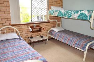 a room with two bunk beds and a table at Traveller's Palms no 8 - Bring your own linen. in South West Rocks